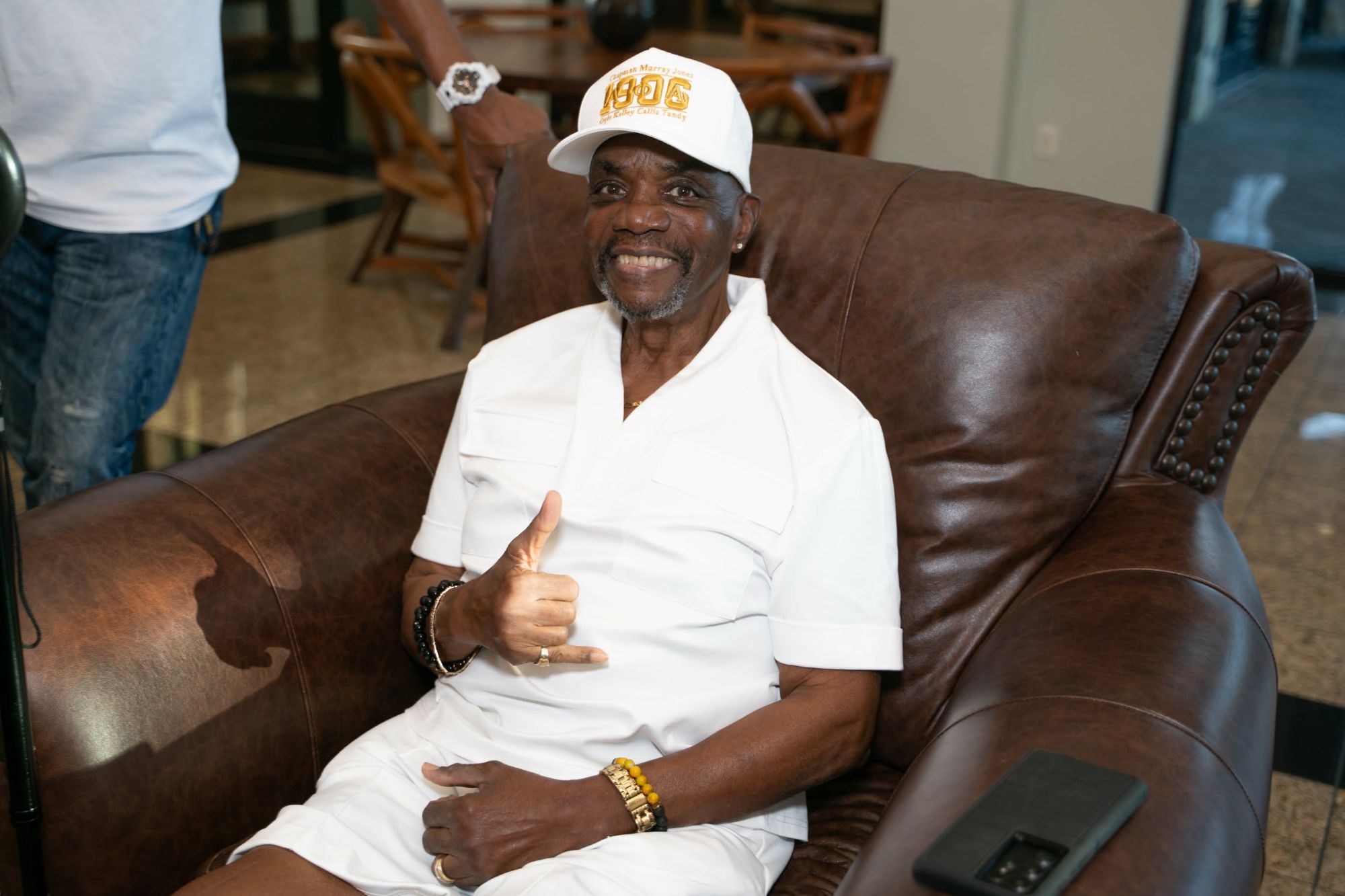 Alpha Phi Alpha elder brother relaxing comfortably, giving a thumbs up — representing the dignity and care the Brother's Keeper program provides